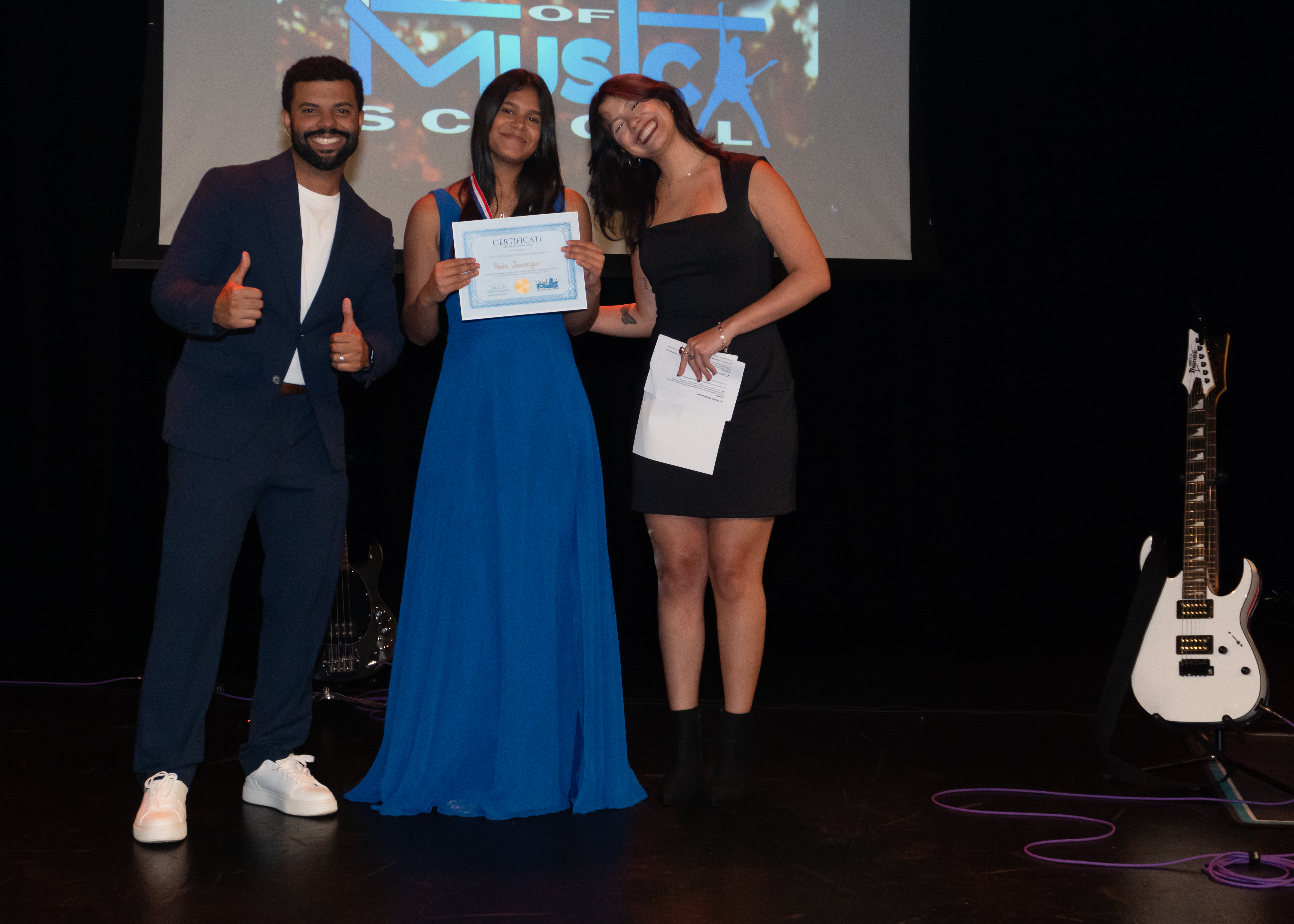 Student receiving certificate on stage with instructors